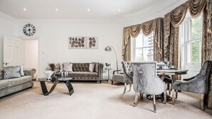 A living room with a sofa, armchairs, a coffee table, and a dining table.