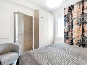 Une chambre à coucher avec un lit, une chaise, une armoire et une fenêtre donnant sur un beau paysage.