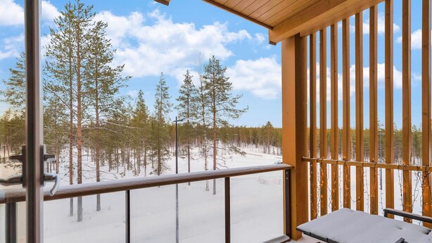 Een balkon met uitzicht op een besneeuwd bos.