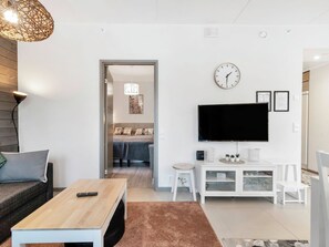 Un salon moderne doté d’un téléviseur à écran plat, d’une table basse, d’un canapé et d’un coin repas avec une table et des chaises.