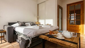 A modern bedroom with a convertible sofa bed, a wooden table with breakfast items, and a large mirror. - Apt CourmayeurC44 w/MontBlanc view Parking, Chamonix, France (Chamonix)