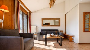 A modern living room with a sofa, a coffee table, and a couch. There is a window with curtains, a mirror on the wall, and a wooden bench. - Apt CourmayeurC44 w/MontBlanc view Parking, Chamonix, France (Chamonix)