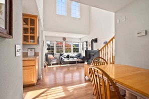 A spacious living area with a wooden dining table, a sofa, and a television.
