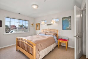 A bedroom with a wooden bed, a nightstand, a window, and a door.