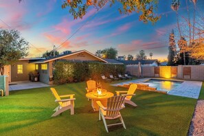 A backyard with a pool, outdoor seating, and a well-maintained lawn.