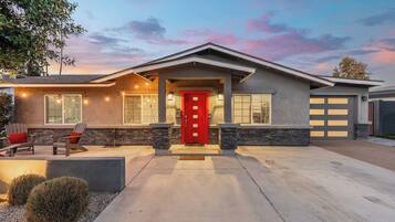 A modern house with a red door, stone accents, and a well-lit driveway.