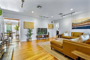 Un salon moderne avec un plancher en bois, un canapé, une table basse et un téléviseur.