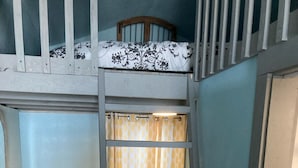 A bunk bed with a ladder, a small bench, and a fluffy rug.