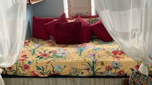 A bedroom with a bed covered in floral bedding, a wooden headboard, and a white furry rug. - Delightful Tiny Cabin (Pikeville)