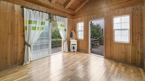 Una habitación con paneles de madera, suelo de madera, un tocador blanco con espejo y vistas a una terraza con mobiliario exterior.
