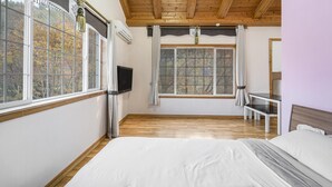Un dormitorio con una cama grande, un televisor y una ventana con vistas a árboles.