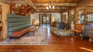 A rustic interior with a wooden bench, a sofa, a dining table, and a staircase. - Log Cabin sleeps 20 with hot tub, EV Charger, firepit (Ahwahnee)
