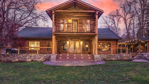 A log cabin with a stone foundation, a front porch, and a large front door. - Log Cabin sleeps 20 with hot tub, EV Charger, firepit (Ahwahnee)