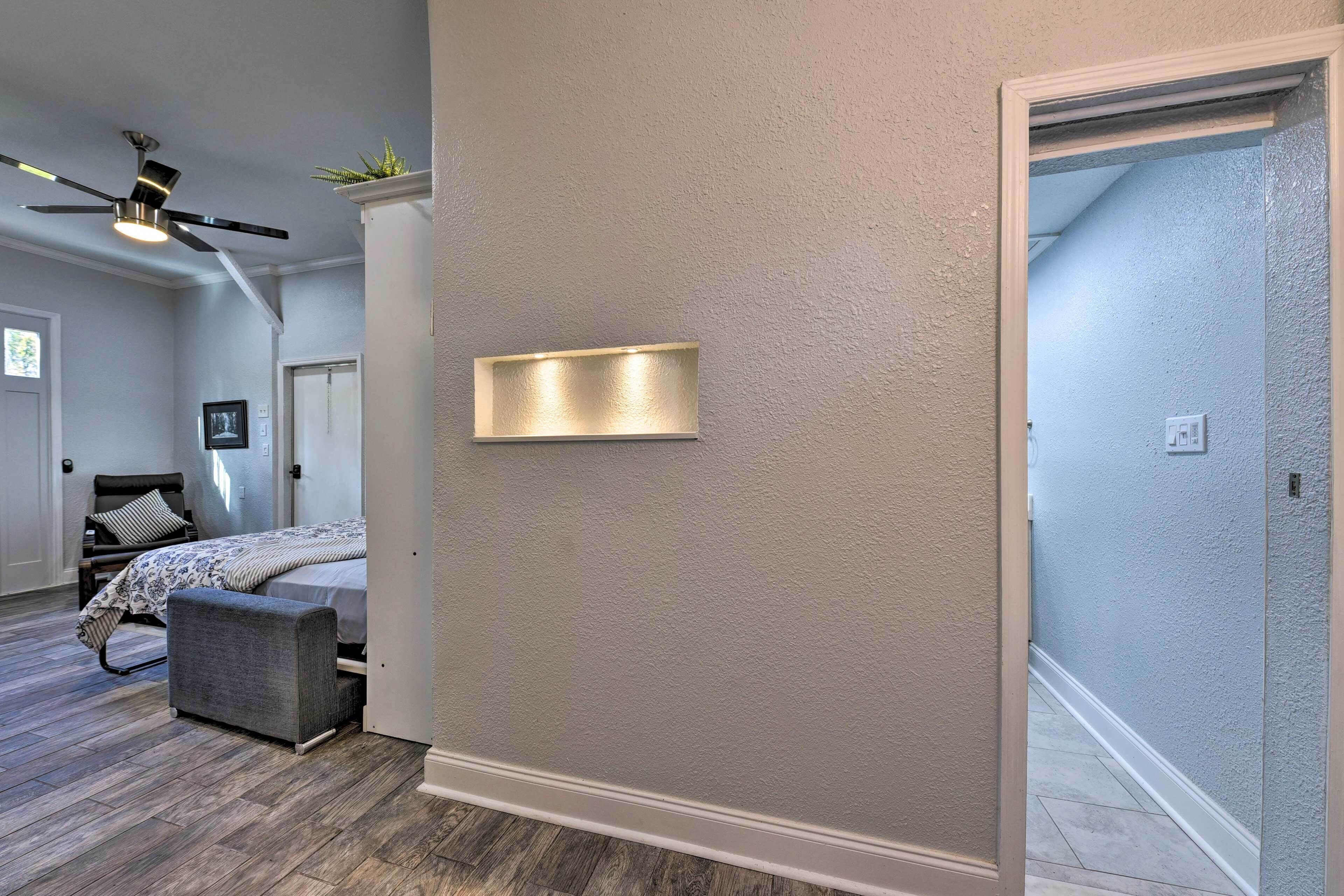A bedroom with a bed, a bench, a ceiling fan, and a wall-mounted light fixture.