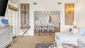 Habitación de hotel con cama, televisor, zona de comedor con mesa y sillas, y un candelabro.