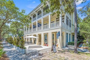 A two-story building with a balcony, outdoor seating, and a signboard. - Ave 30A - 2BR/2BA WaterColor Town Center Condo - Sleeps 4 - Beach Club Access (Santa Rosa Beach)