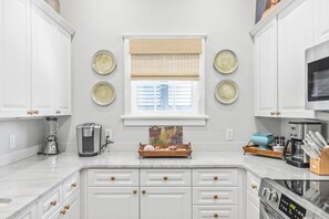 A kitchen with white cabinets, a coffee maker, a blender, and a microwave.