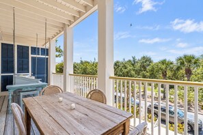 A wooden table with chairs on a balcony with a view of palm trees and parked cars. - Ave 30A - 2BR/2BA WaterColor Town Center Condo - Sleeps 4 - Beach Club Access (Santa Rosa Beach)