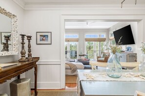 A room with a wooden table, a mirror, and a television mounted on the wall. - Ave 30A - 2BR/2BA WaterColor Town Center Condo - Sleeps 4 - Beach Club Access (Santa Rosa Beach)