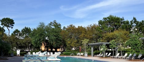 A pool area with lounge chairs and a pergola.