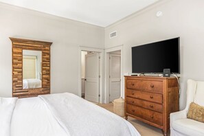 Un dormitorio con una cama, un aparador, un televisor y un espejo.