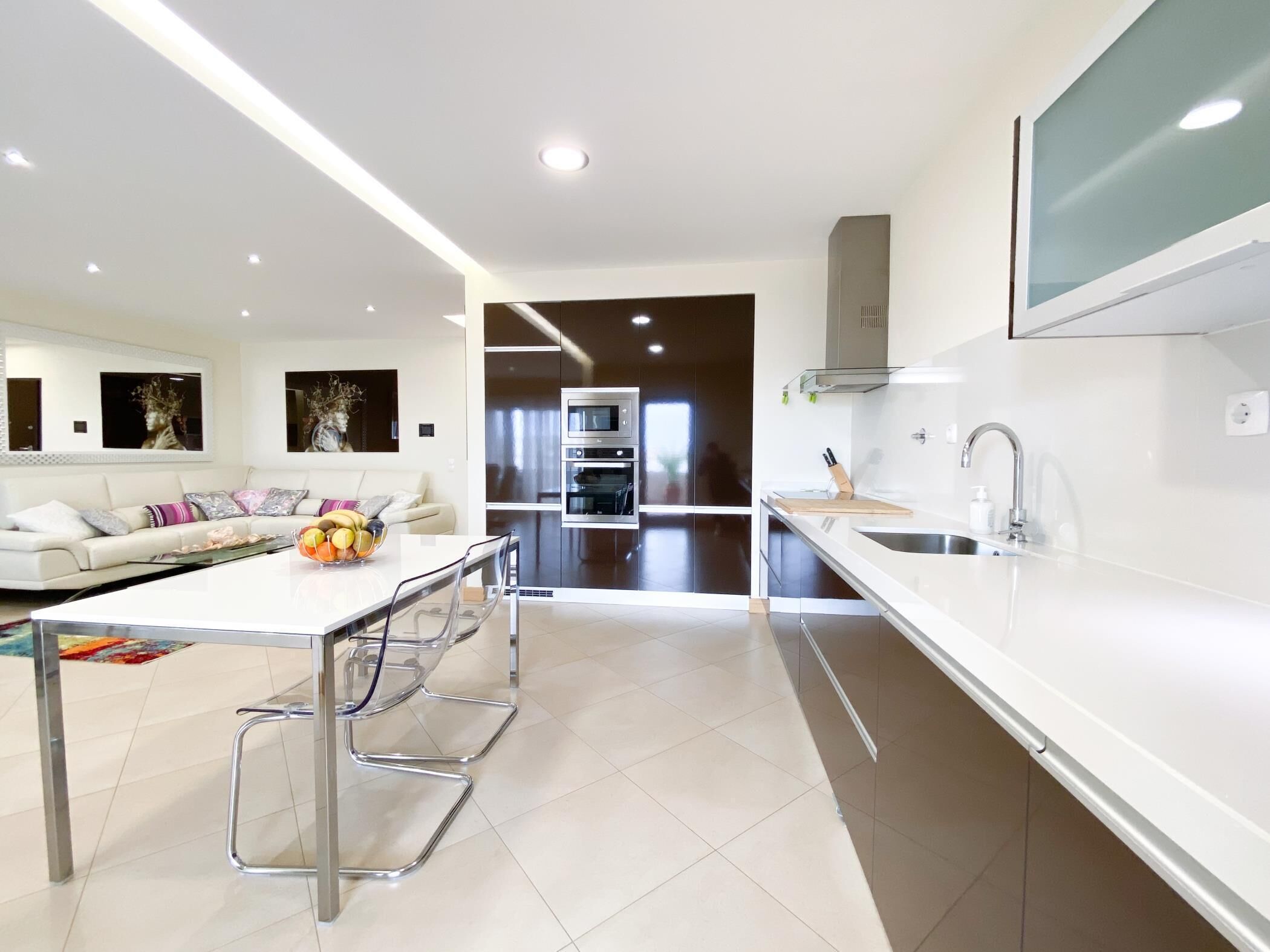 A modern kitchen with a central island, stainless steel appliances, and a large window.