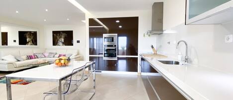 A modern kitchen with a central island, stainless steel appliances, and a large window.