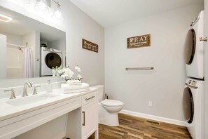 A modern bathroom with a white sink, mirror, and toilet. There are two wall-mounted signs, one saying "Please be neat and wipe the seat" and the other "PRAY without ceasing." A small plant is on the sink counter. - Step-Free Home w/ Fire Pit - 3 Miles to USC! (Columbia)
