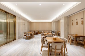 A modern dining area with wooden tables and chairs, a glass partition, and recessed ceiling lighting. - Ji Hotel (Xi'an)