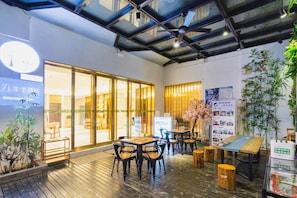 A hotel interior with a wooden floor, tables, chairs, and a large glass door entrance. - Ji Hotel (Xi'an)