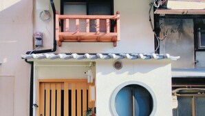 A traditional Japanese house with a wooden gate, a small balcony, and a round window. - miyu Ebisu Independent Japanese hotel (Osaka)