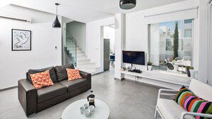 A modern living room with a sofa, coffee table, and TV. There is a staircase leading to another level. - Protaras Holiday Villa Ccv2 (Protaras)