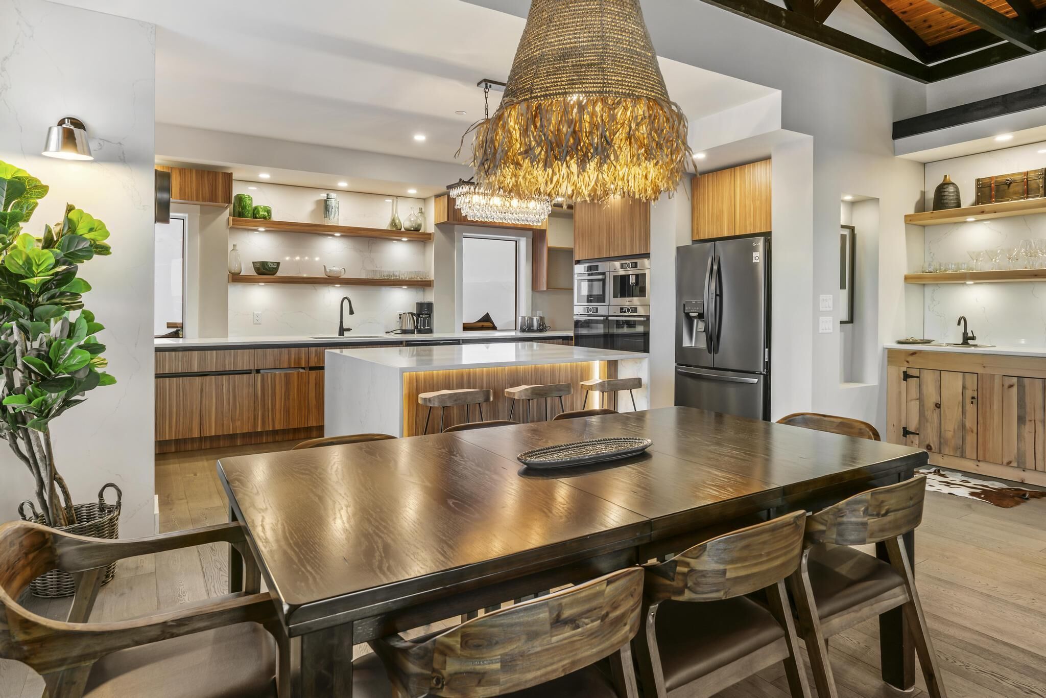 A modern kitchen with a central island, wooden cabinets, stainless steel appliances, and a hanging light fixture.