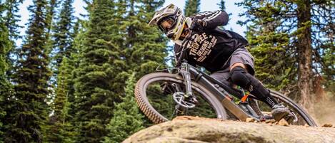 A mountain biker navigating a rocky terrain with dense forest in the background.