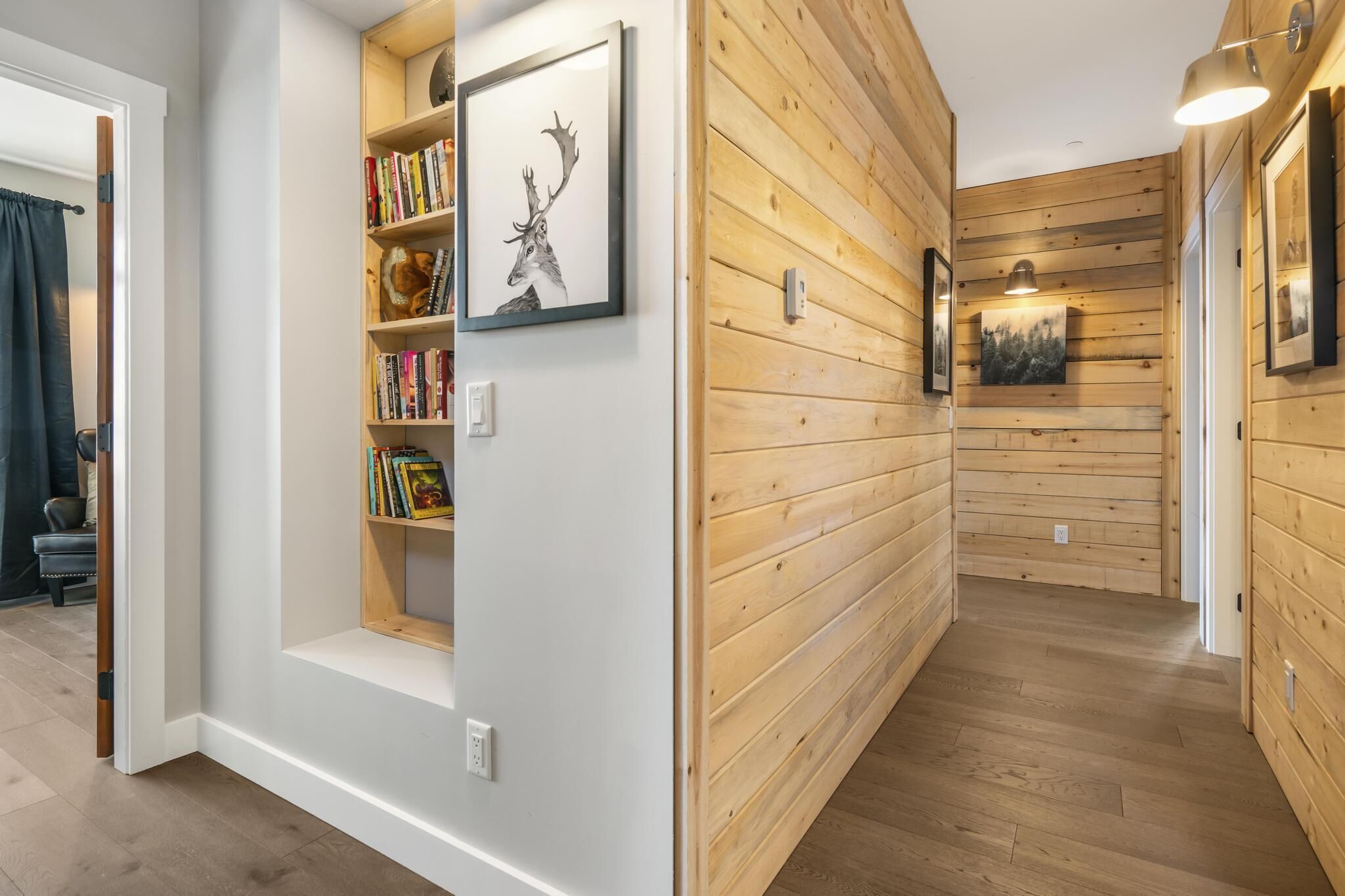 A hallway with wooden paneling and a bookshelf with books and framed artwork.