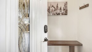 Une porte avec un panneau en verre, un système de verrouillage à clavier et un banc dans un couloir.