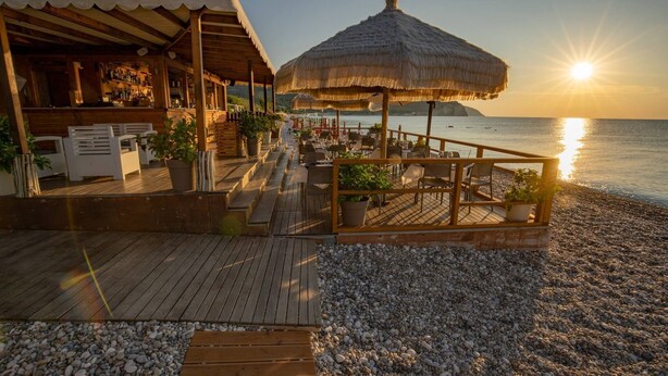 A wooden deck with outdoor seating, a bar area, and a thatched umbrella.