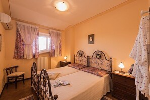 Ein Schlafzimmer mit einem Bett, Nachttischen, einem Sessel und einem Fenster mit Vorhängen.