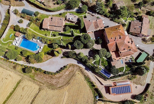 An aerial view of a residential area with multiple houses, a swimming pool, and solar panels.
