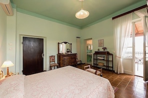 A bedroom with a large bed, a dresser, a mirror, and a chandelier.