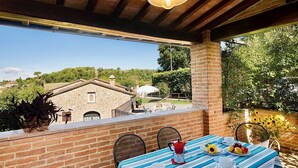 Eine Terrasse mit Tisch für zwei Personen, mit Blick auf ein Backsteingebäude und Grünflächen.