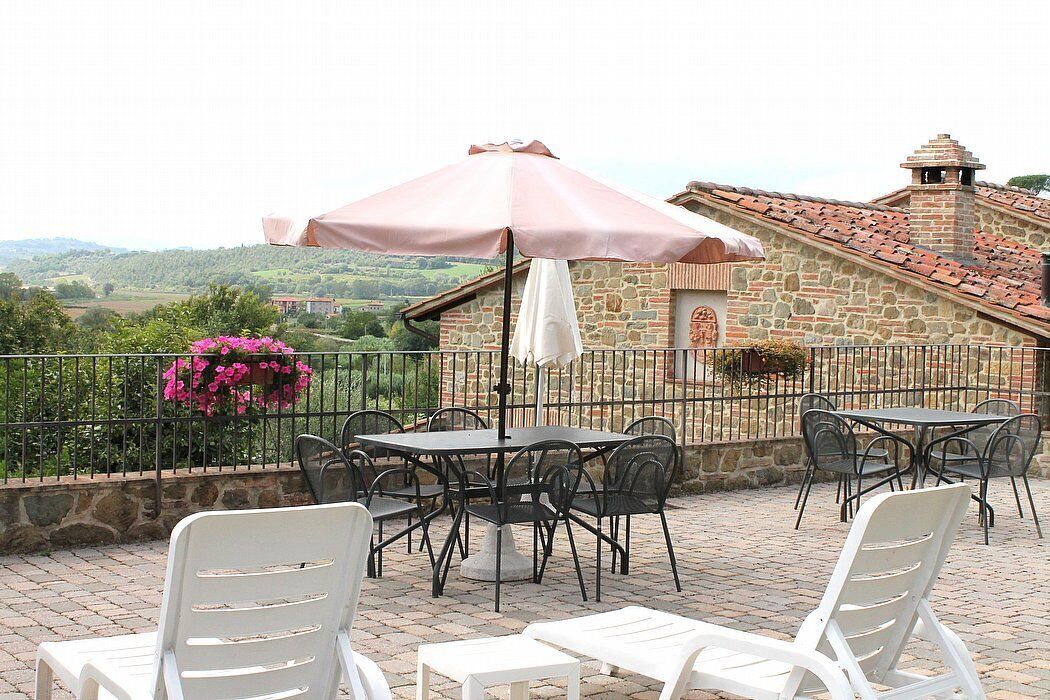 Une terrasse extérieure avec des murs en pierre, une cheminée en pierre et une vue sur la campagne.
