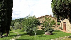 A stone building with a red roof, surrounded by a well-maintained lawn and trees.