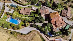 An aerial view of a residential area with multiple houses, a swimming pool, and solar panels.