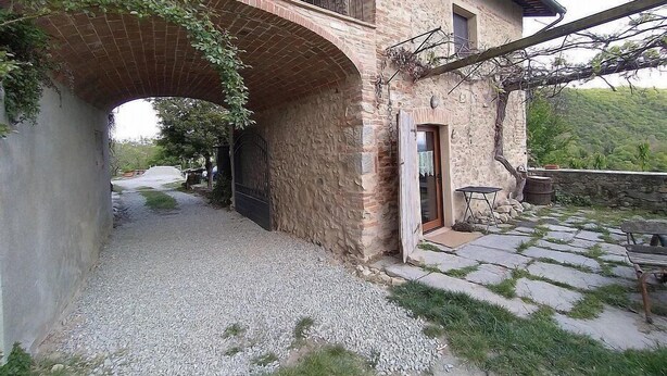 A rustic stone building with a brick archway leading to a gravel path.