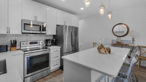 A modern kitchen with white cabinetry, stainless steel appliances, and pendant lighting. - Private Beach | 1 minute walk to Beach! | Beautifully updated 1 bedroom condo | Sleeps 6 | Wi-Fi (Santa Rosa Beach)