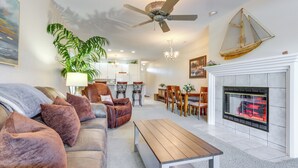 A modern living room with a sofa, coffee table, and fireplace. There is a dining area with chairs and a chandelier. - Private Boat Slip: Family-Friendly Lazy Days Condo (Osage Beach)