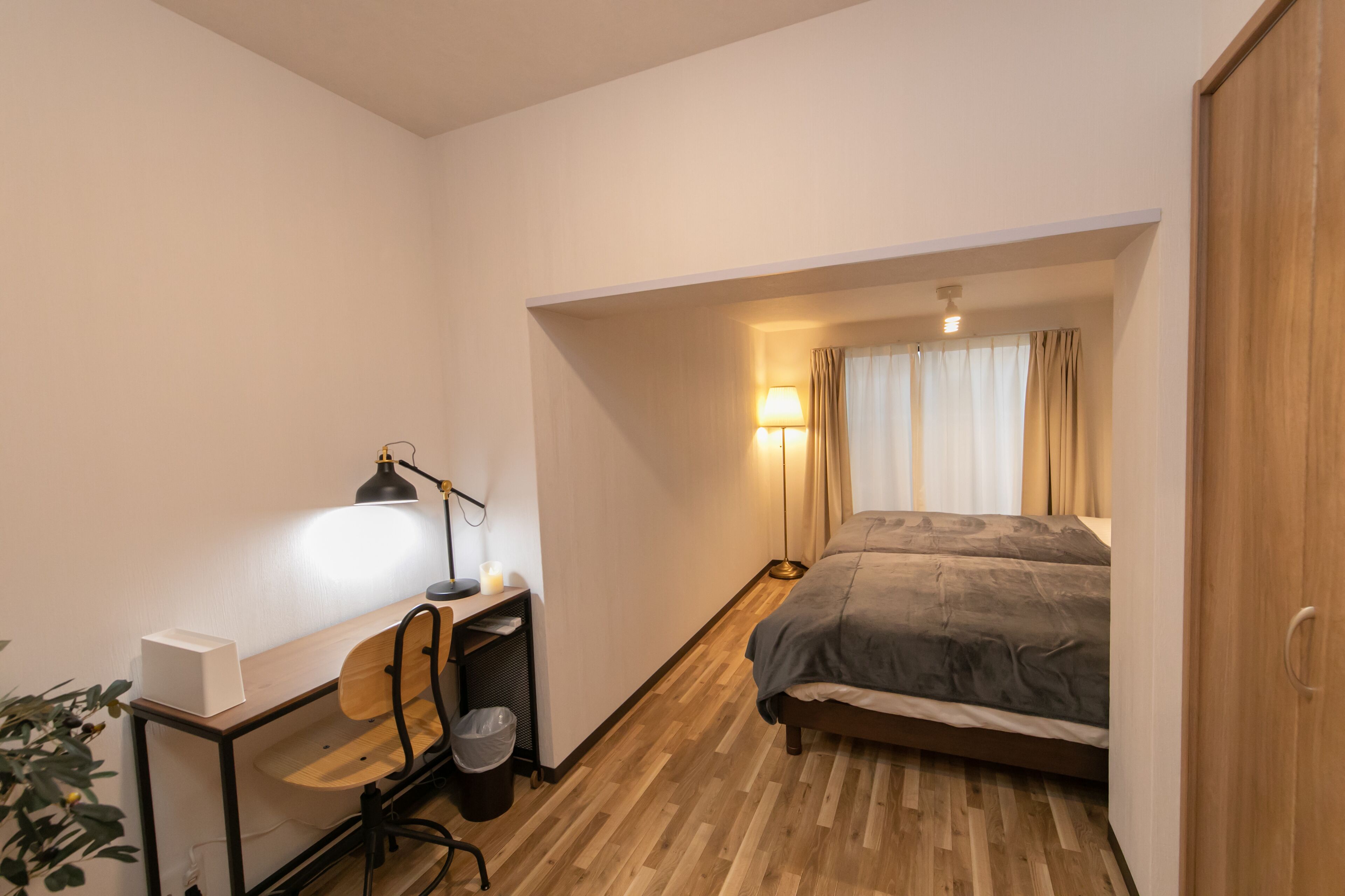 A compact bedroom with a wooden desk, chair, and a bed with a grey duvet.