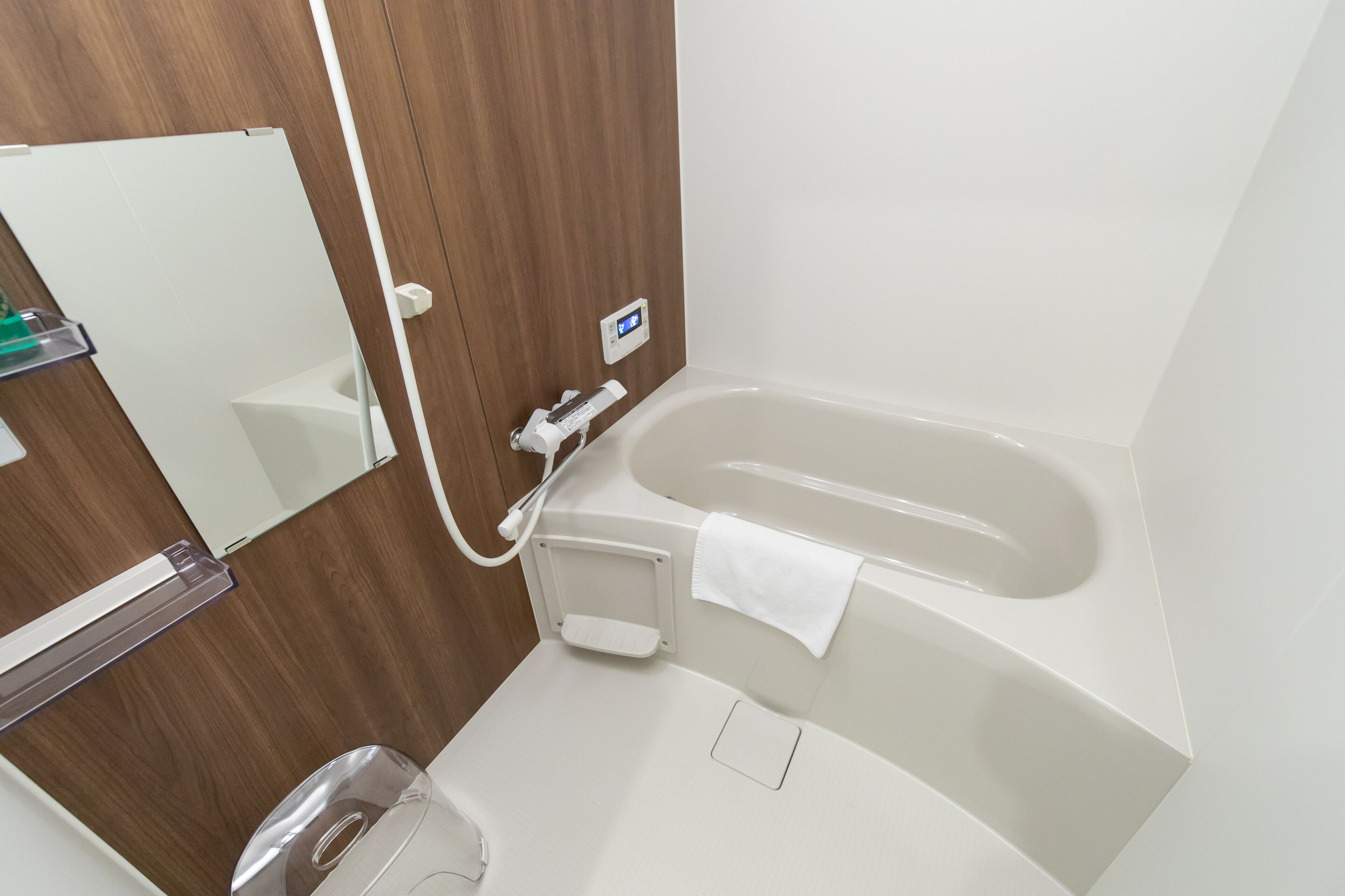 Une salle de bain moderne avec un meuble-lavabo en bois, une baignoire blanche et un miroir.