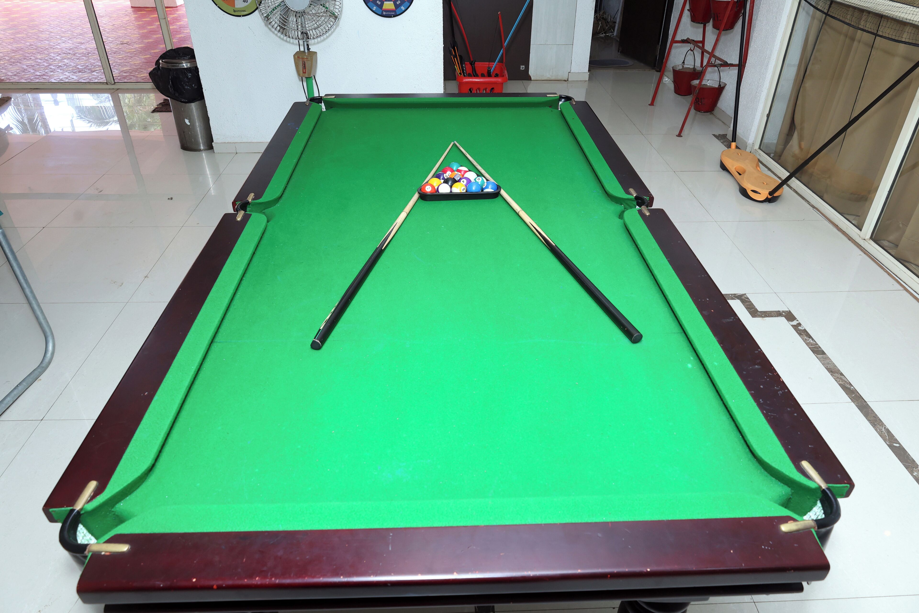 A pool table with a green felt surface, two pool cues, and a colorful set of balls.